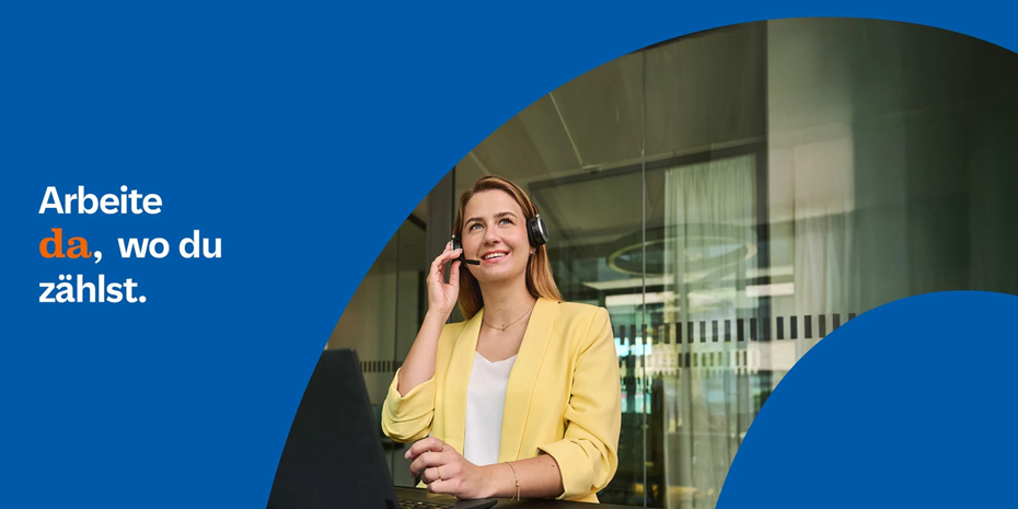 Frau mit gelbem Blazer sitzt vor Laptop und spricht mit Headset in modernem Büro, im Hintergrund eine moderne Glasfassade